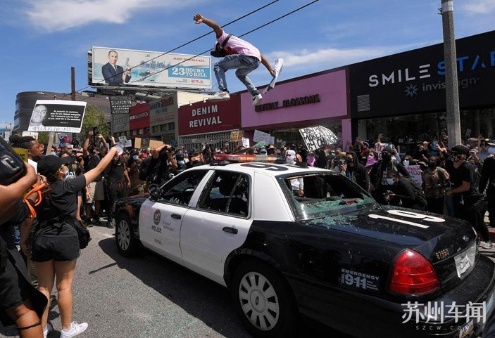 洛杉矶,一名抗议者跳上一台福特crown victoria警车的车顶.